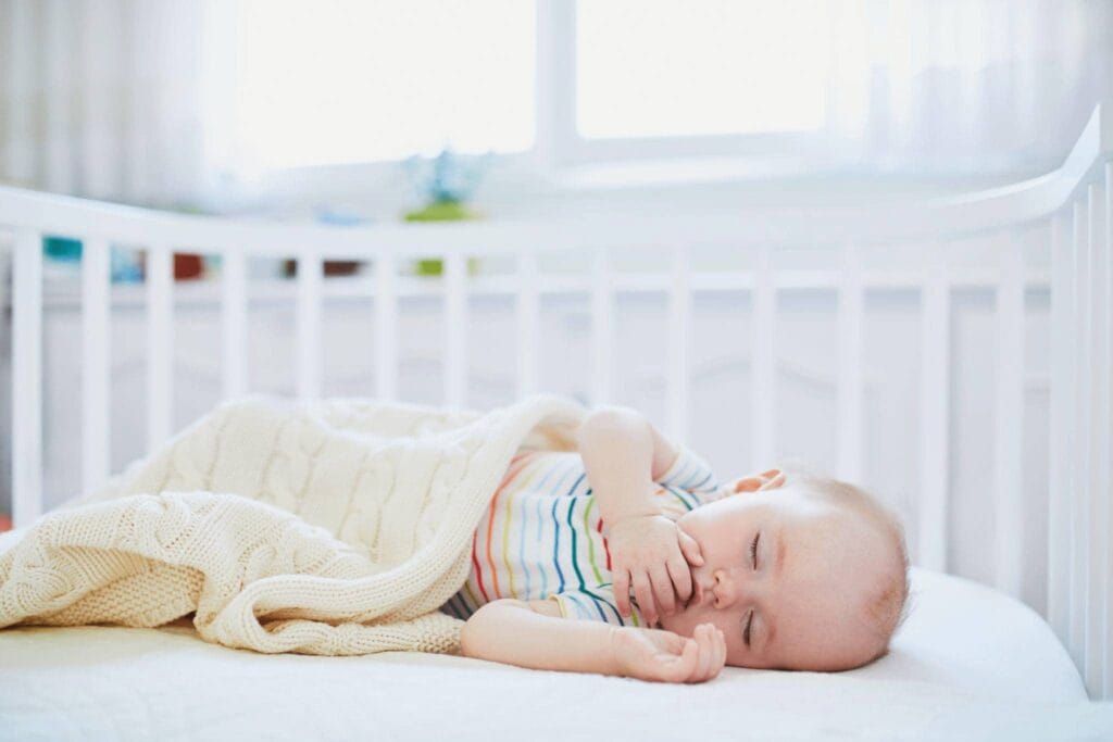 when can babies sleep with a blanket